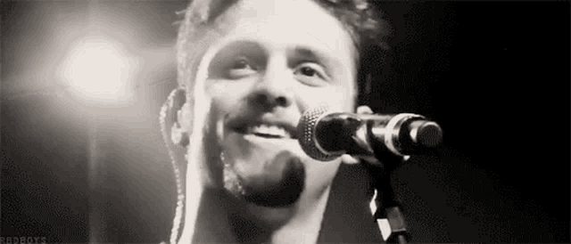 a man is singing into a microphone and smiling .
