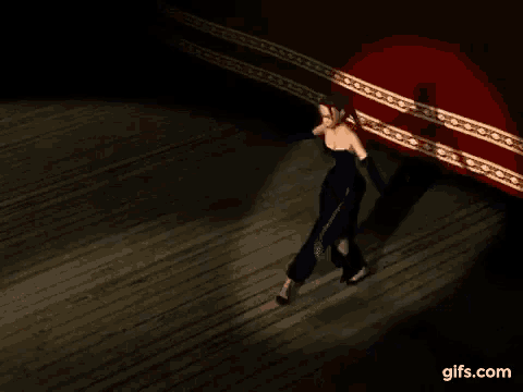 a woman in a blue dress and gloves is walking on a wooden floor in front of a red curtain .