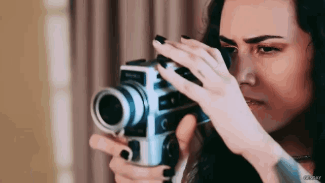 a woman is taking a picture with a camera that has the letter c on the front