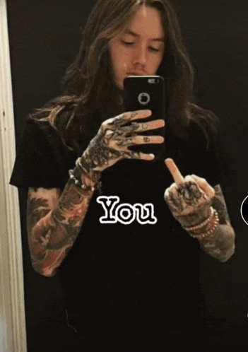 a man taking a picture of himself with the word you written on his shirt