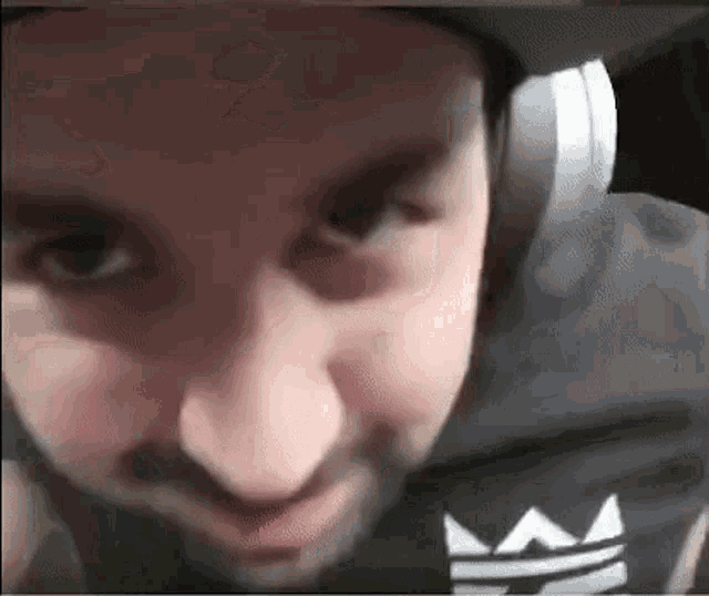 a man with a beard is wearing headphones and a hat and smiling .