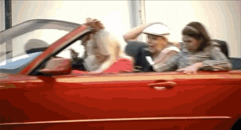 a group of people are sitting in a red sports car