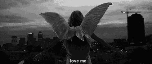 a black and white photo of a woman with angel wings and the words love me .