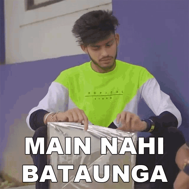 a man in a neon green shirt is holding a piece of aluminum foil with the words main nahi batalunga below him