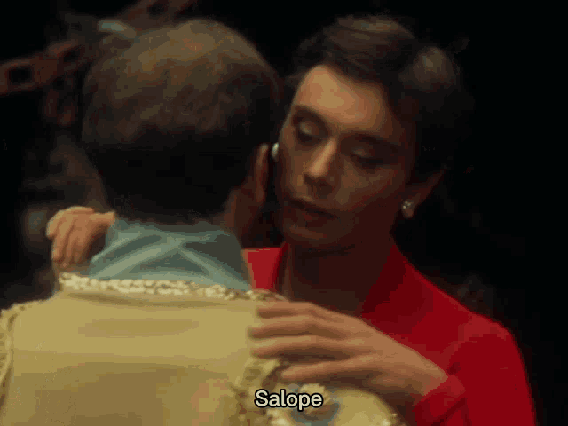 a woman in a red dress is hugging a man in a tan suit and the word salope is on the bottom right