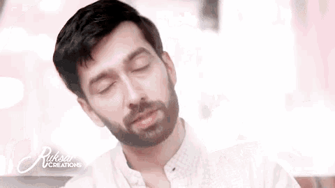 a man with a beard is sitting with his eyes closed in front of an ad for ruksar creations