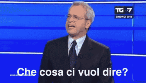 a man in a suit and tie stands in front of a blue background and says che cosa ci vuol dire