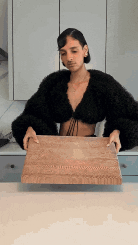 a woman in a black top is holding a cutting board