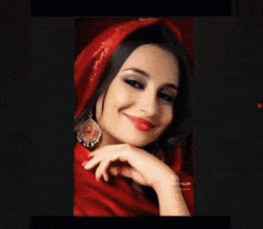 a woman wearing a red scarf and earrings smiles for the camera .