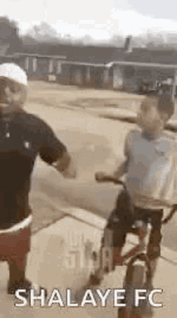 a man and a child are holding hands while riding a bike down the street .