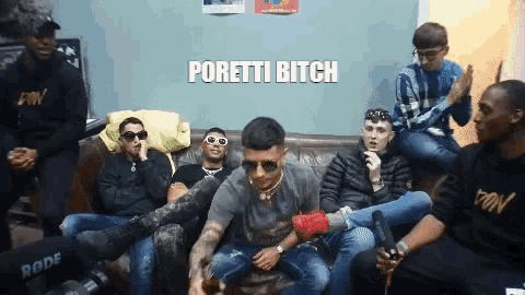 a group of young men are sitting on a couch and one of them is wearing sunglasses and says poretti bitch