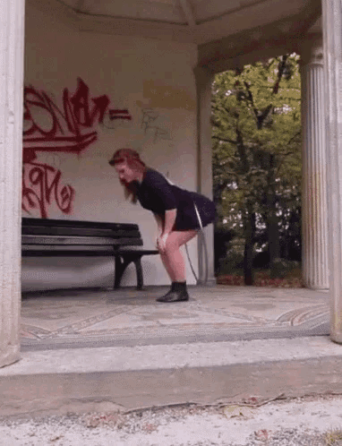 a woman squatting in front of a wall with graffiti that says ' s.m.r. '