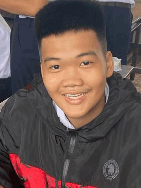 a young man wearing a black and red jacket is smiling .