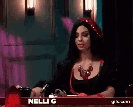 a woman in a witch costume is sitting in front of a sign that says nelli g on it