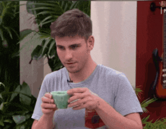 a man in a blue shirt is holding a green cup