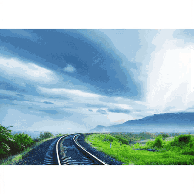a train track with mountains in the background and a blue sky