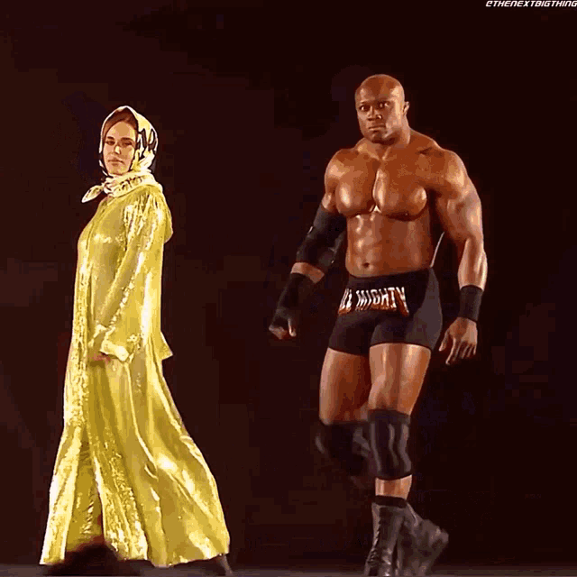 a woman in a yellow dress stands next to a wrestler wearing black shorts with the word ncw on them