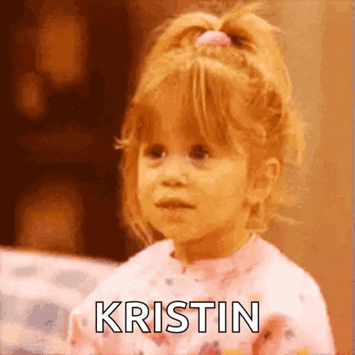 a little girl is wearing a pink sweater and making a funny face .