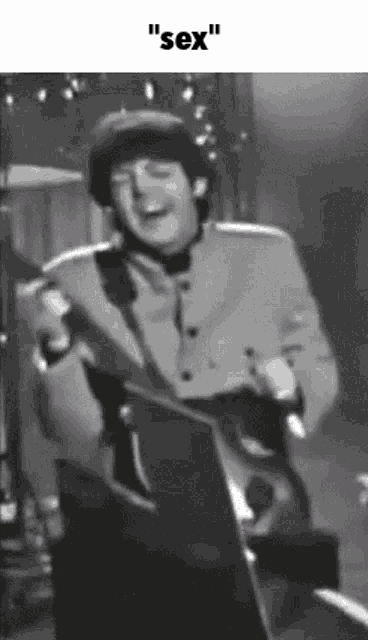 a black and white photo of a man playing a guitar and singing with the words " sex " above him .