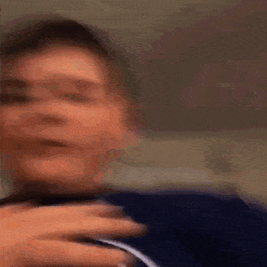 a young boy in a blue shirt is holding a pair of headphones in his hand .