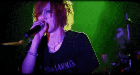 a woman with red hair is standing in front of a green and purple background .