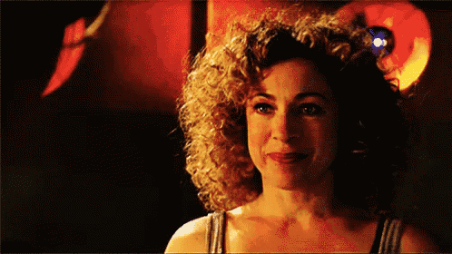 a woman with curly hair is smiling in front of a red light .