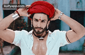 a man with a beard is wearing a red turban and earrings .