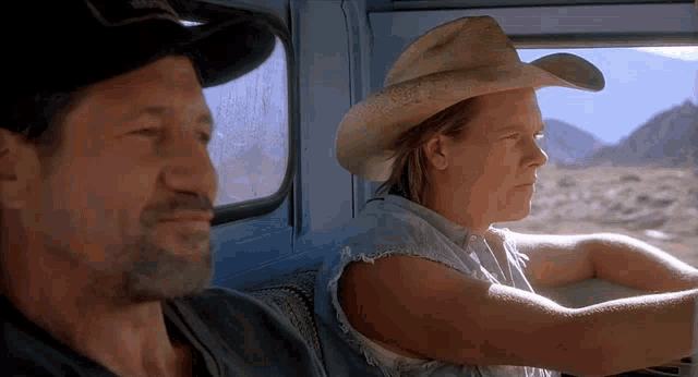 a man in a cowboy hat sits next to another man in a truck
