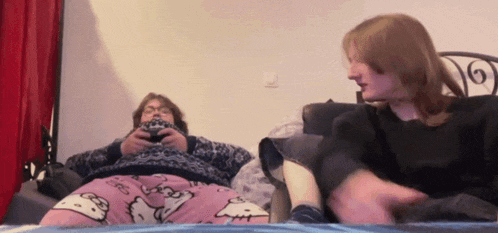 a man in a hello kitty pajama sits on a bed