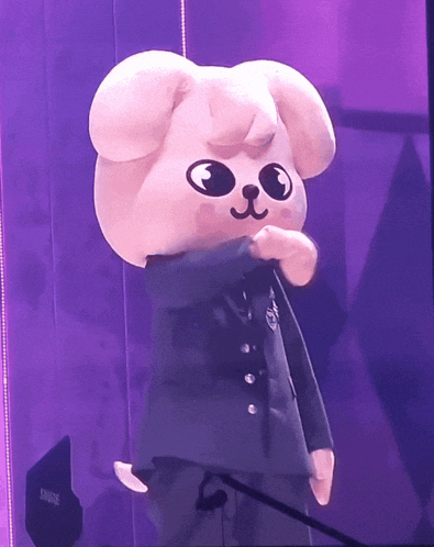 a stuffed animal standing in front of a shure speaker