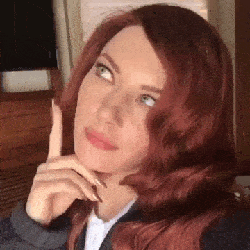 a woman with red hair and blue eyes is thinking about something while looking up .