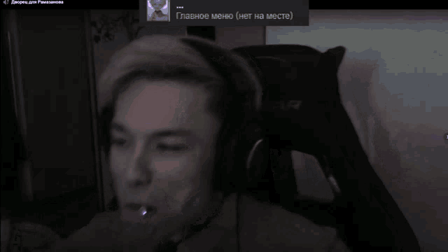 a man wearing headphones is smoking a cigarette with a russian text behind him that says главное меню