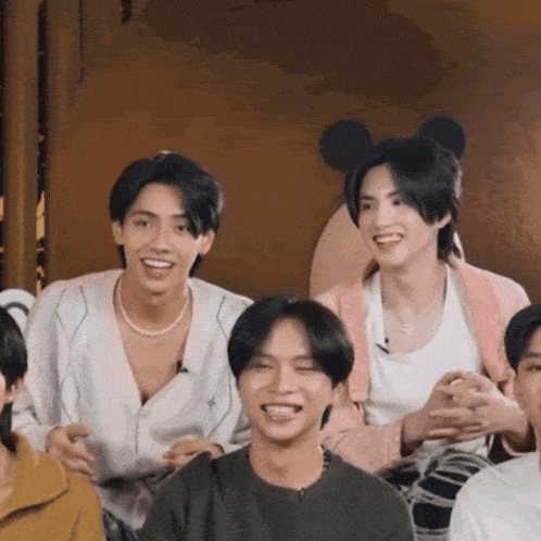 a group of young men are posing for a picture and one of them is wearing a mickey mouse headband