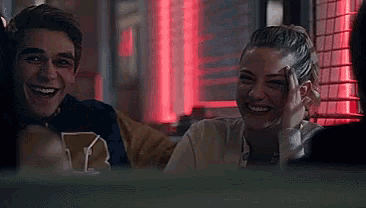 a man and a woman are sitting next to each other and smiling in a restaurant .