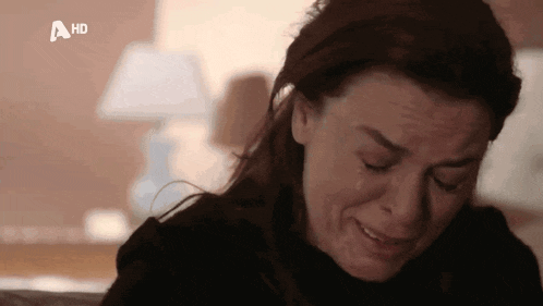 a woman is crying while sitting on a couch with a hd logo in the corner .