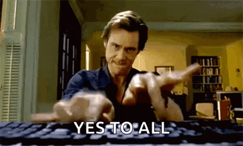 a man is typing on a keyboard and pointing at the camera while saying yes to all .