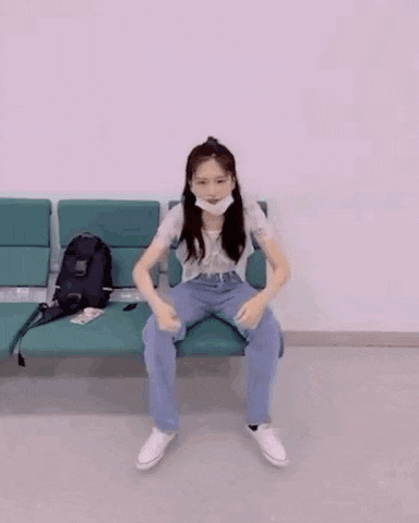 a woman wearing a mask is sitting on a couch in a waiting room .