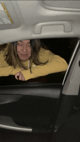 a woman in a yellow nike sweatshirt leaning out of a car window