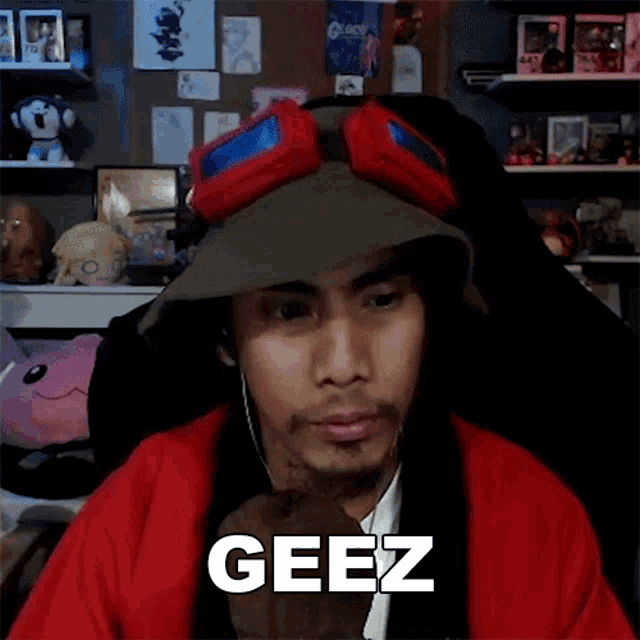 a man wearing a hat and goggles with the word geez on his face