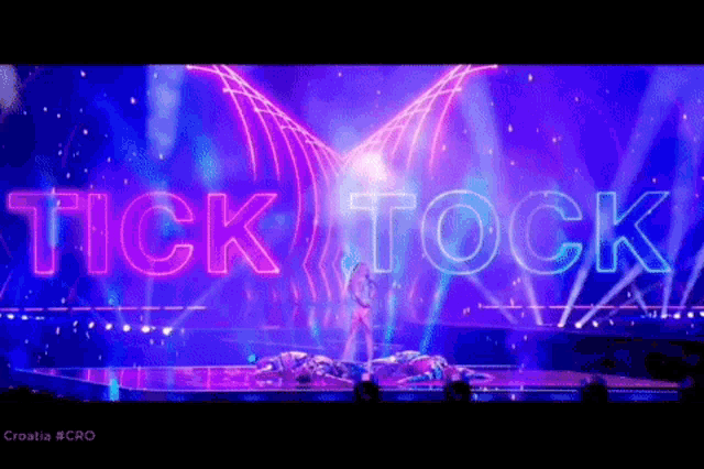 a neon sign that says tick tock is lit up on a stage