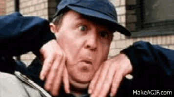 a man wearing a blue hat is making a funny face with his hands .