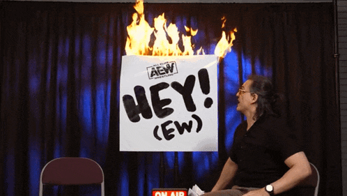a man sitting in front of a sign that says hey ( ew )