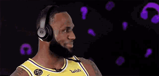 a basketball player wearing headphones and a yellow jersey is smiling .
