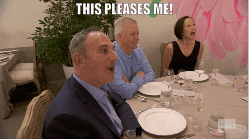 a group of people sitting at a table with plates and wine glasses and the caption this pleases me