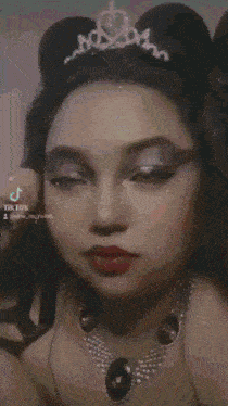 a woman is wearing a tiara and a necklace with the letter r on the bottom right