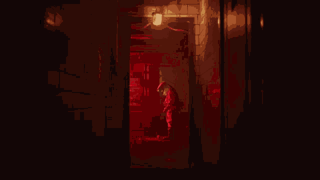 a person is sitting in a dark room with a red light behind them