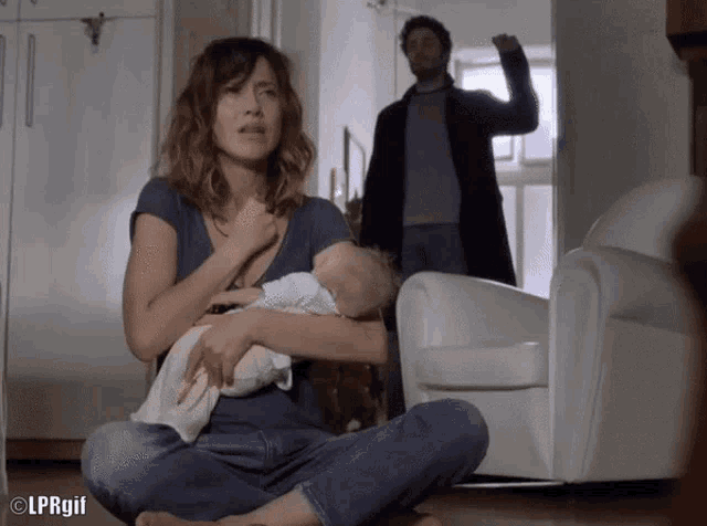 a woman sitting on the floor holding a baby with lprgif written on the bottom right