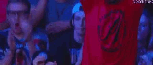 a group of people are sitting in a stadium holding their arms in the air .