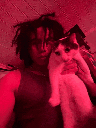 a man with dreadlocks is holding a cat that has a tag that says ' i love you ' on it
