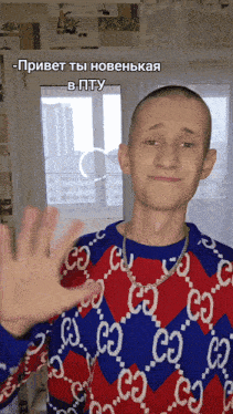 a man wearing a red and blue gucci sweater waves